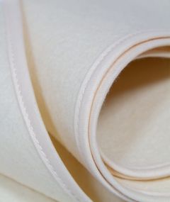 Gros plan sur la texture du protège-matelas en laine pour bébé, doux et absorbant.