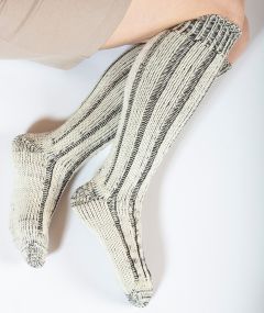 Chaussettes longues en laine mérinos et coton biologique portées par un mannequin, mettant en avant leur confort et leur performance, capturées en studio avec un focus sur le pied.