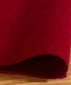 Tissu en feutre de laine rouge en cours d’utilisation, prêt à être découpé ou cousu, matière saine et solide pour projets créatifs