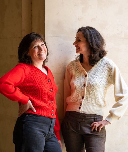 Deux femmes portant chacune un gilet en laine mérinos, couleurs sorbier et écru, style élégant et confortable pour toutes les occasions.