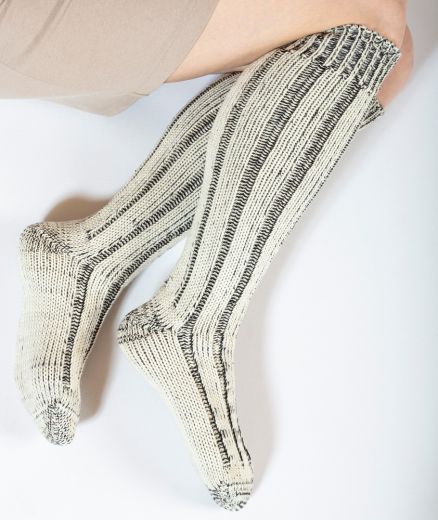 Chaussettes longues en laine mérinos et coton biologique portées par un mannequin, mettant en avant leur confort et leur performance, capturées en studio avec un focus sur le pied.