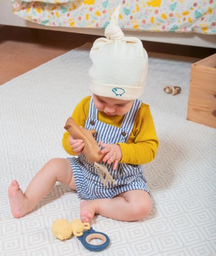 bébé qui joue portant le bonnet lutin en laine mérinos bio coloris écru, vue face