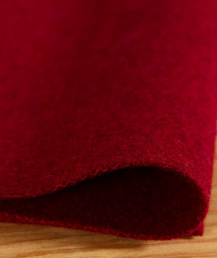 Tissu en feutre de laine rouge en cours d’utilisation, prêt à être découpé ou cousu, matière saine et solide pour projets créatifs