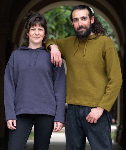 Homme et femme portant chacun un pull à capuche en laine mérinos française, couleurs mousse et basalte, style décontracté et confortable pour l’hiver.
